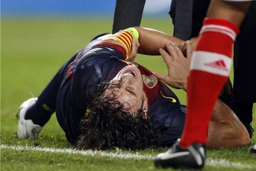 Carles Puyol, bek Barcelona, mengerang kesakitan akibat mengalami cedera siku saat menghadapi Benfica di laga Grup G Liga Champions di Stadion Luz, Lisbon, Selasa (2/10). 