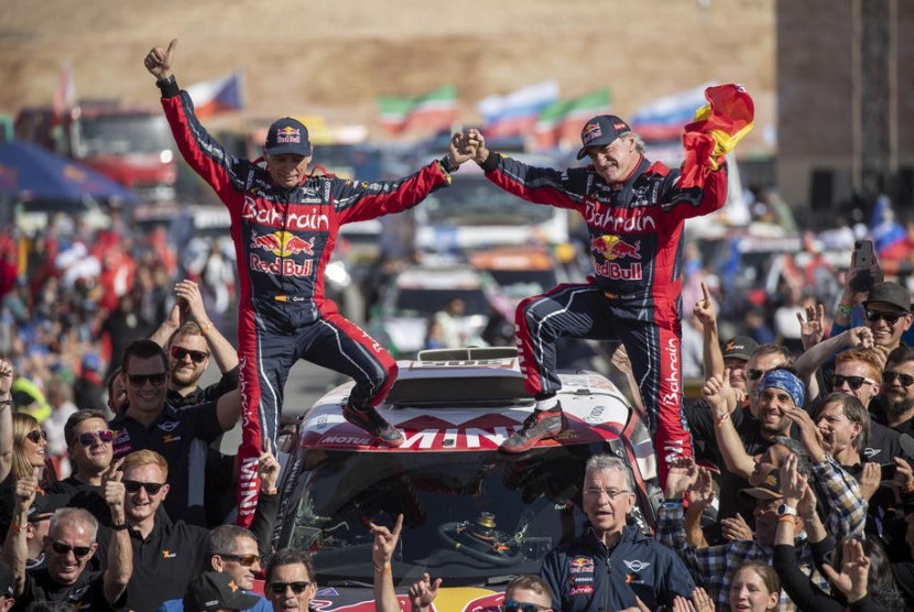 Carlos Sainz (R) dan co-driver Lucas Cruz berpose setelah menjuarai Reli Dakar 2020 kategori mobil.