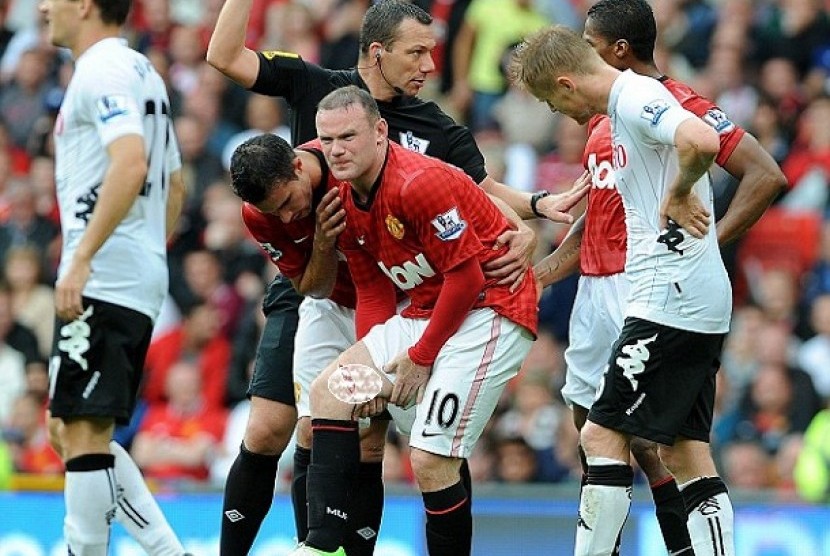 CEDERA EMPAT PEKAN. Striker Manchester United, Way Rooney (tengah) meringis kesakitan karena pahanya robek dalam laga lanjutan Liga Primer Inggris, Sabtu (25/8). Cedera itu diprediksi membuat Rooney absen selama empat pekan.