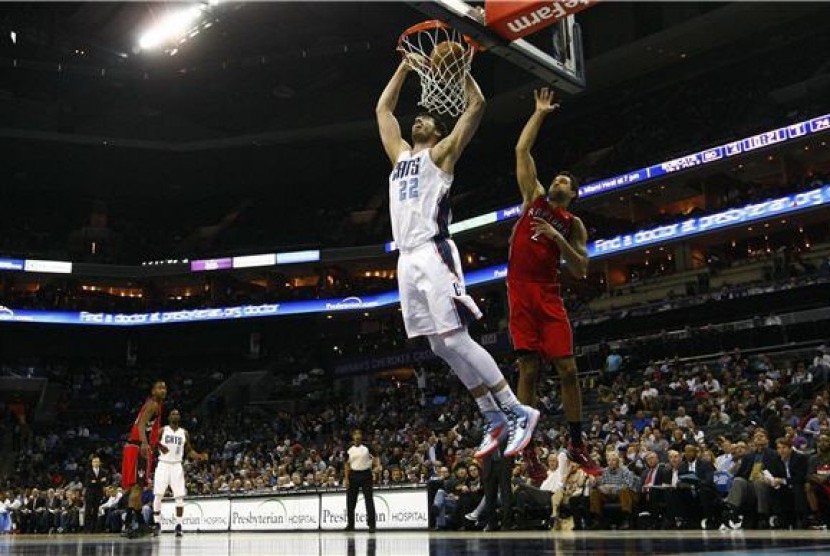 Center Charlotte Bobcats, Byron Mullens, memperagakan dunks dalam kepungan small forward Toronto Raptors, Landry Fields (kanan), dalam laga NBA di Charlotte, North Carolina, Rabu (20/3). 