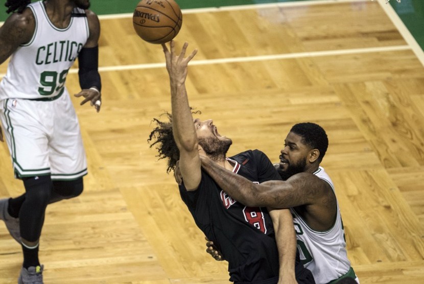 Center Chicago Bulls, Robin Lopez (tengah) berebut bola dengan dua pemain Boston Celtics pada laga playoff NBA, di TD Garden, Selasa (18/4).