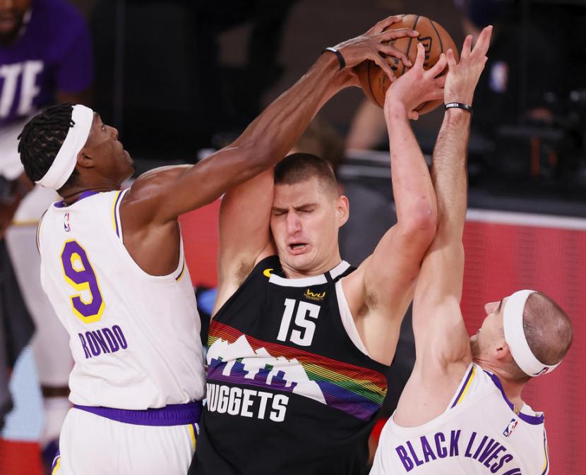 Center Denver Nuggets, Nikola Jokic (tengah), diapit dua pemain Los Angeles Lakers dalam laga play-off final Wilayah Barat NBA.