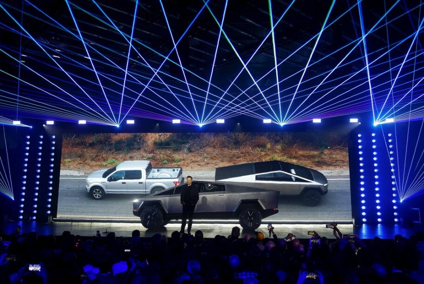 CEO Tesla Elon Musk mengenalkan Tesla Cybertruck di California. Tampak di belakang latar foto Cybertruck menarik mobil Ford. 