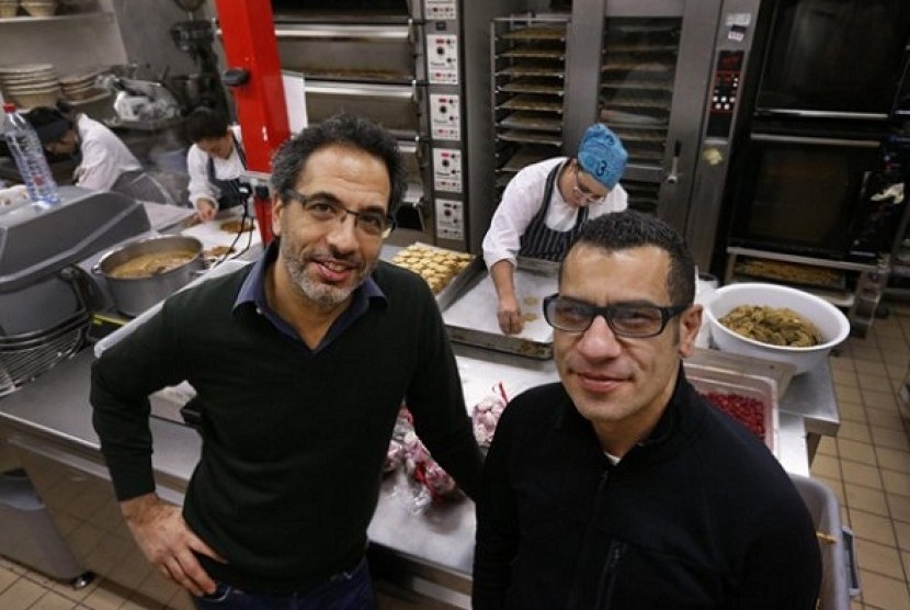 Chefs Yotam Ottolenghi (left) and Sami Tamimi pose for the photographer at their company's bakery in London. One chef is Israeli, the other a Palestinian.   