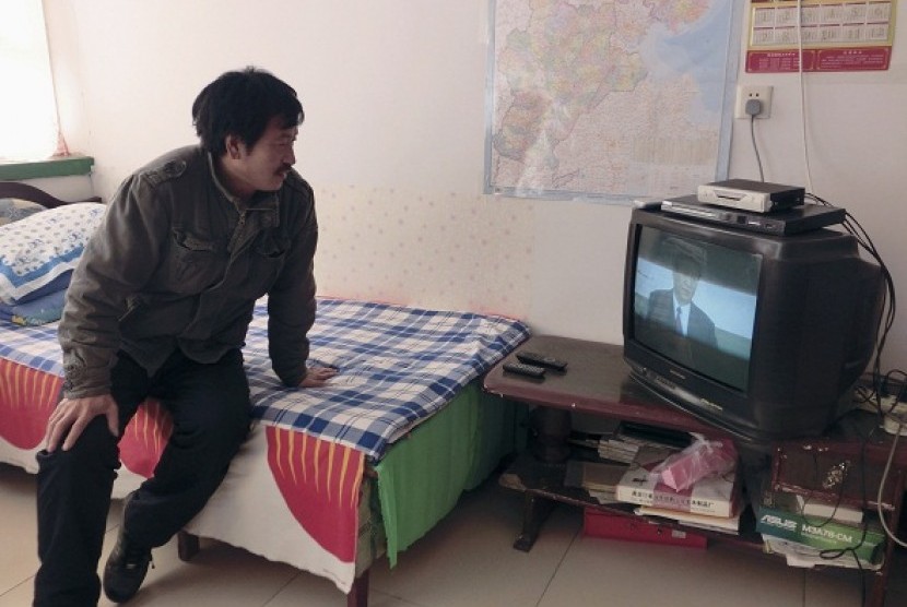  Chen Yongjiang, a fruit and vegetable farmer, sits on a bed as he watch a live broadcast of China's new Communist Party General Secretary Xi Jinping speaking during a media event to introduce the newly elected China's Politburo Standing Committee members,