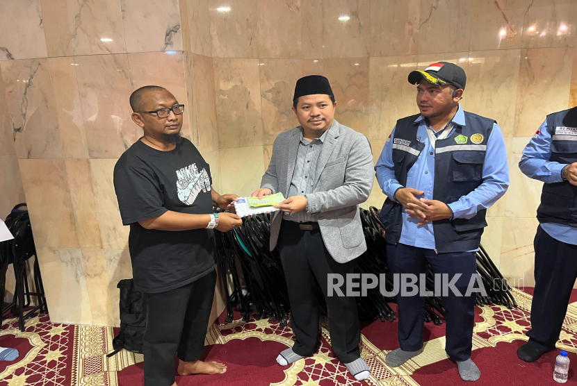 Chief Operating Officer BPKH Limited, Iman Nimatullah (tengah) bersama Ketua PPIH Arab Saudi Ali Machzumi memberikan  kompensasi uang pengganti makan kepada salah satu perwakilan rombongan jamaah haji(kanan) di Hotel 614, Makkah, Kamis (12/6/2025).