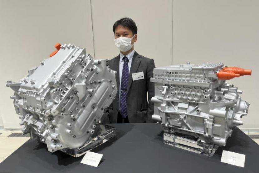 Chief Powertrain Engineer Nissan, Masaki Takaoka, berfoto bersama dua contoh pengembangan powertrain elektrik “X-in-1” buatan Nissan di kantor pusatnya di Yokohama di Yokohama, Jepang, Selasa, 7 Maret 2023.