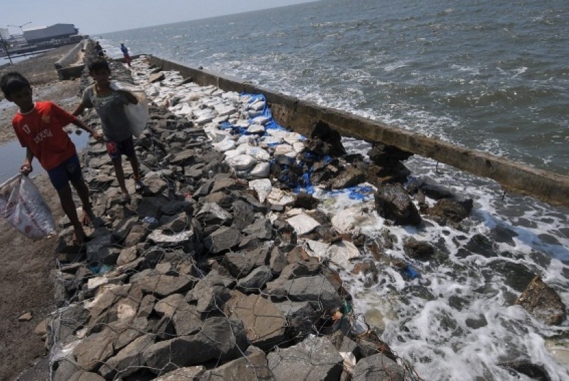 Children pass the  burst dyke in Muara Baru, Jakarta. Government will build giant sea wall ahead of plan in 2014 instead of 2020. (illustration)