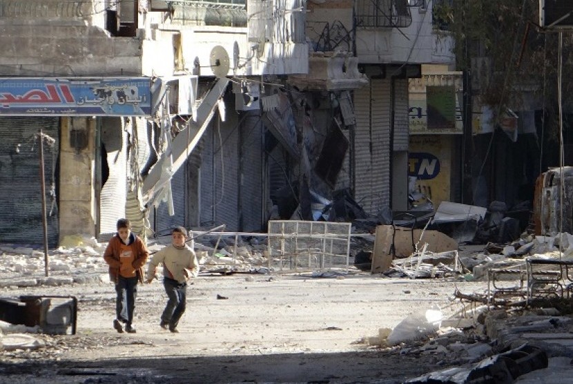 Children run along a street damaged by what activists said was a Syrian Air Force air strike in the Aleppo district of Salaheddine December 5, 2012. Picture taken December 5, 2012.   