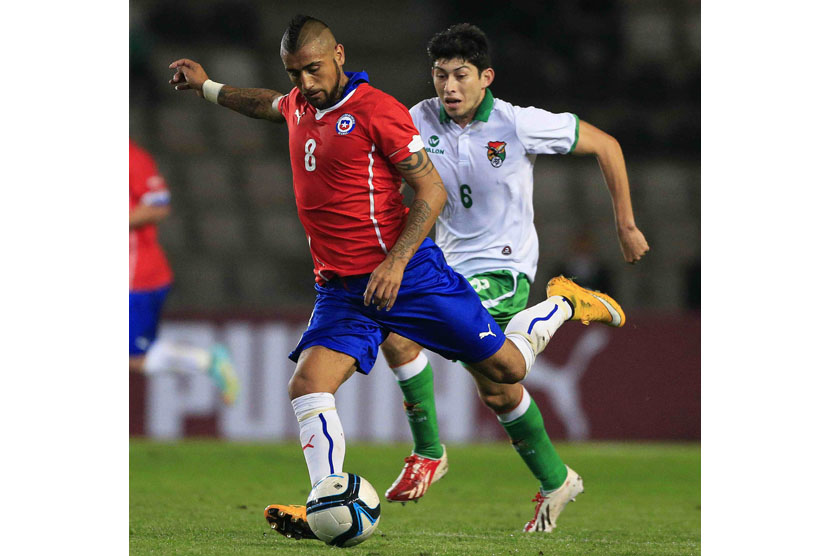 Chile's Arturo Vidal (L) and Bolivia's Pedro Azogue fight for the ball during their international friendly soccer match in Coquimbo city, north of Santiago, October 14, 2014. 