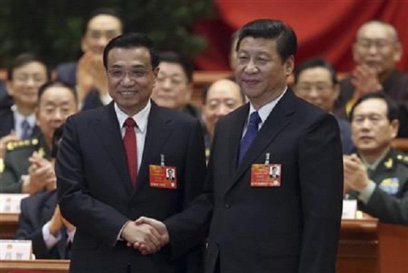 China's President Xi Jinping shakes hands with China's newly elected Premier Li Keqiang (left) as other delegates clap during the fifth plenary meeting of the first session of the 12th National People's Congress (NPC) in Beijing March 15, 2013. 