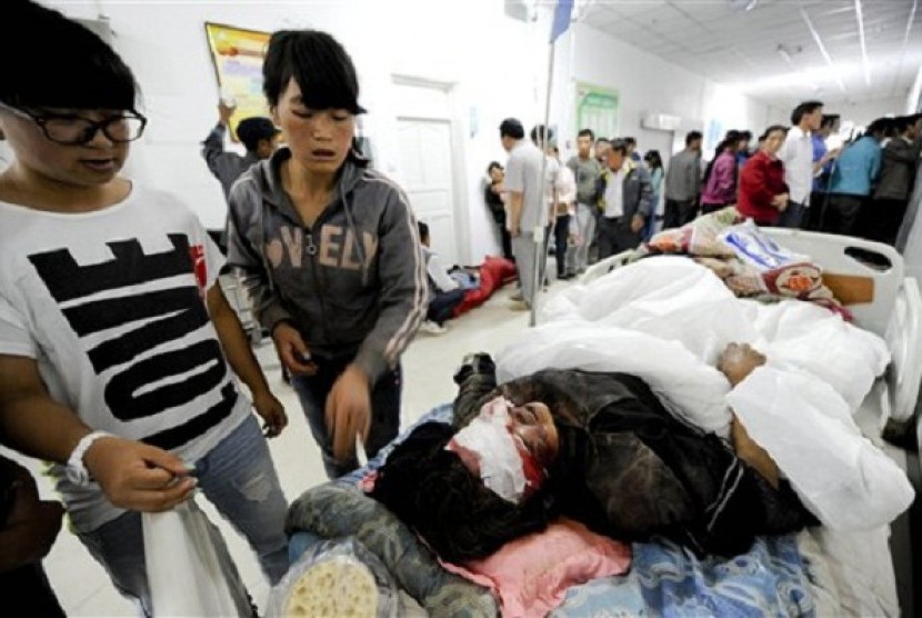 Chinese women look at a person injured by an earthquake resting on a bed at a hospital in Minxian county in Dingxi city in northwest China's Gansu province on Monday, July 22, 2013. 
