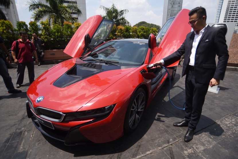 Corporate Communication Specialist BMW Group Indonesia Ismail Ashlan mengisi bahan bakar listrik mobil BMW i8 Protonic Red Edition yang merupakan edisi terbatas disela penyerahan mobil tersebut kepada pelanggan di Jakarta, Kamis (20/4). 