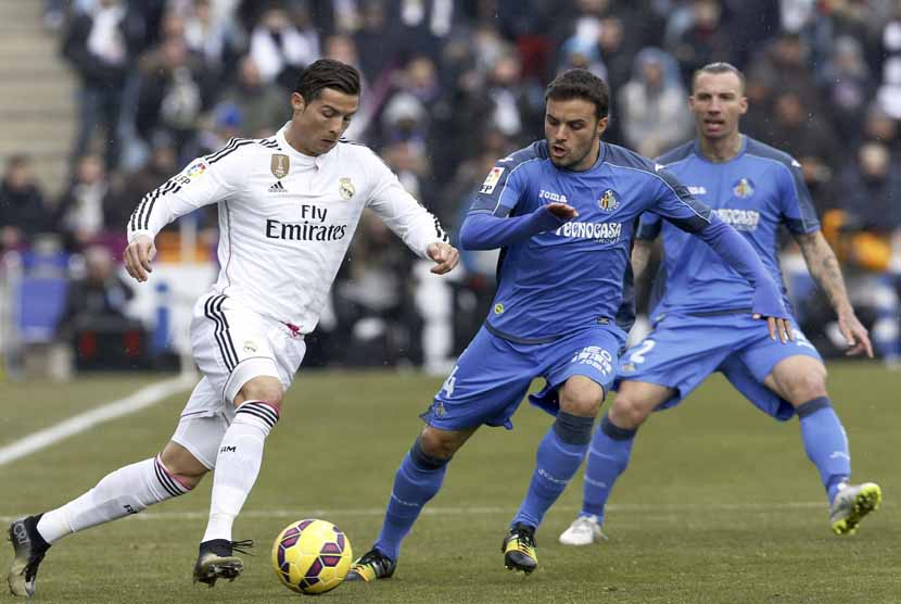 Cristiano Ronaldo (kiri), winger andalan Real Madrid, mencoba melewati hadangan pemain Getafe dalam laga La Liga Spanyol di Stadion Alonso Perez, Getafe, Ahad (18/1). 