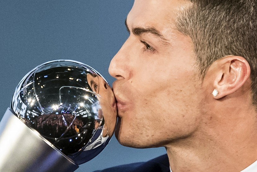 Cristiano Ronaldo mencium trofi pemain terbaik 2016 versi FIFA, Senin (9/1).