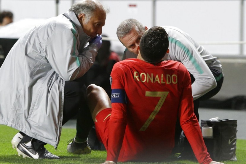 Cristiano Ronaldo mendapatkan perawatan dari tim medis Portugal saat menderita gangguan otot dalam laga kontra Serbia.