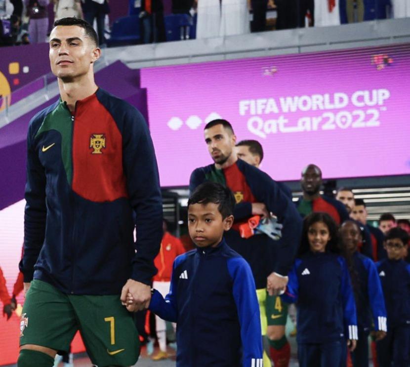 Cristiano Ronaldo pemain asal Portugal menggandeng player escort seorang bocah asal Indonesia. Banyak diaspora Indonesia di Doha Qatar yang ambil bagian sebagai relawan Piala Dunia 2022.