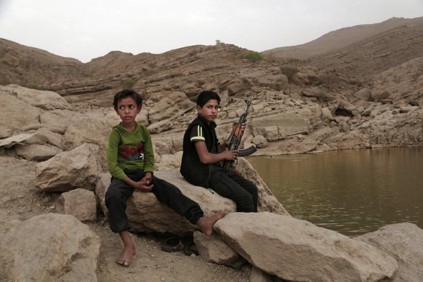 Seorang anak laki-laki memegang senjatanya di bendungan tinggi di Marib, Yaman. 