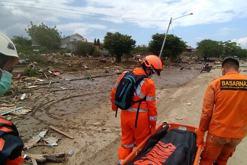 Dalam foto yang dibagikan BASARNAS, Sabtu (29/9), tampak petugas sedang memindahkan korban jiwa di Pantai Wina, setelah gempa dan tsunami terjadi di Kota Palu.