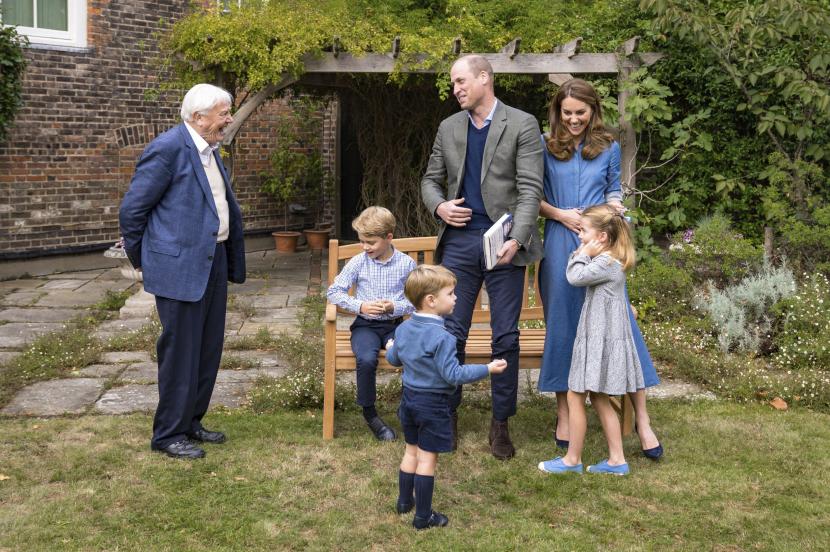 Dalam foto yang dibagikan pada Kamis (24/9), Sir David Attenborough (kiri) berinteraksi dengan keluarga Pangeran William di Istana Kensington. Pangeran George tampak duduk sambil memegang fosil gigi hiu megalodon pemberian Attenborough.