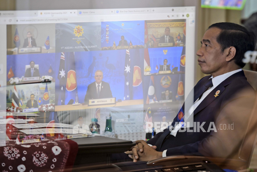 Dalam foto yang dirilis Istana Kepresidenan Indonesia ini, Presiden Indonesia Joko Widodo terlihat melalui pantulan layar TV, mendengarkan Perdana Menteri Australia Scott Morrison berbicara dalam pertemuan virtual KTT ASEAN-Australia.