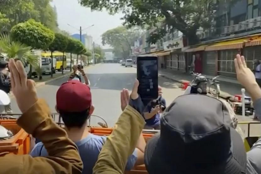 Dalam gambar yang dibuat dari video ini, pengunjuk rasa anti-kudeta menunjukkan salam tiga jari ke arah polisi, di belakang, di Yangon, Myanmar, Sabtu, 27 Februari 2021. Polisi Myanmar pada hari Sabtu bergerak untuk membersihkan pengunjuk rasa anti-kudeta dari jalan-jalan kota terbesar di negara itu Yangon.