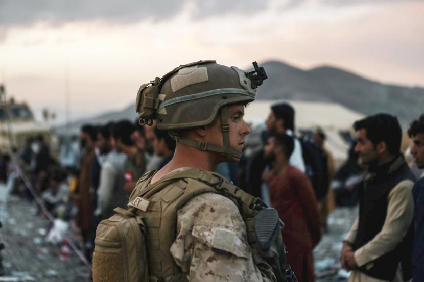  Dalam gambar yang disediakan oleh Marinir AS ini, seorang Marinir yang ditugaskan ke Satuan Tugas-Tanggapan-Pusat Tanggap Krisis Angkatan Udara Tujuan Khusus membantu para pengungsi selama evakuasi di Bandara Internasional Hamid Karzai di Kabul, Afghanistan, Jumat, 20 Agustus 2021.