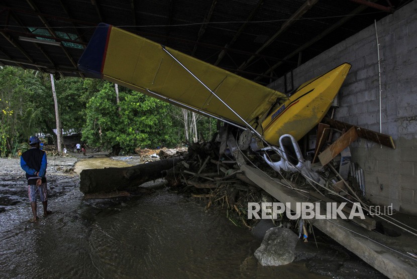 Dampak Banjir Bandang Sentani. Seorang warga berada di dekat pesawat latih yang terdampak banjir bandang di Sentani, Kabupaten Jayapura, Papua, Ahad (17/3/2019).