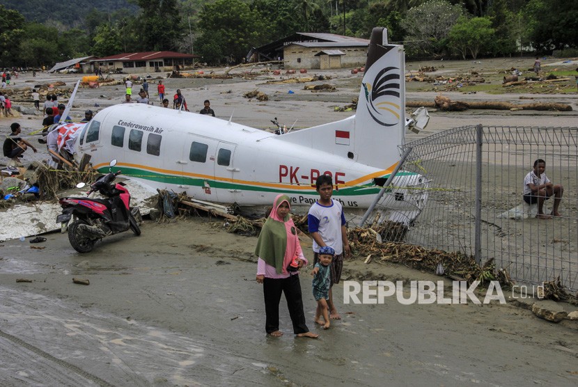 Dampak Banjir Bandang Sentani. Warga berada di dekat pesawat udara yang terdampak banjir bandang di Sentani, Kabupaten Jayapura, Papua, Ahad (17/3/2019).