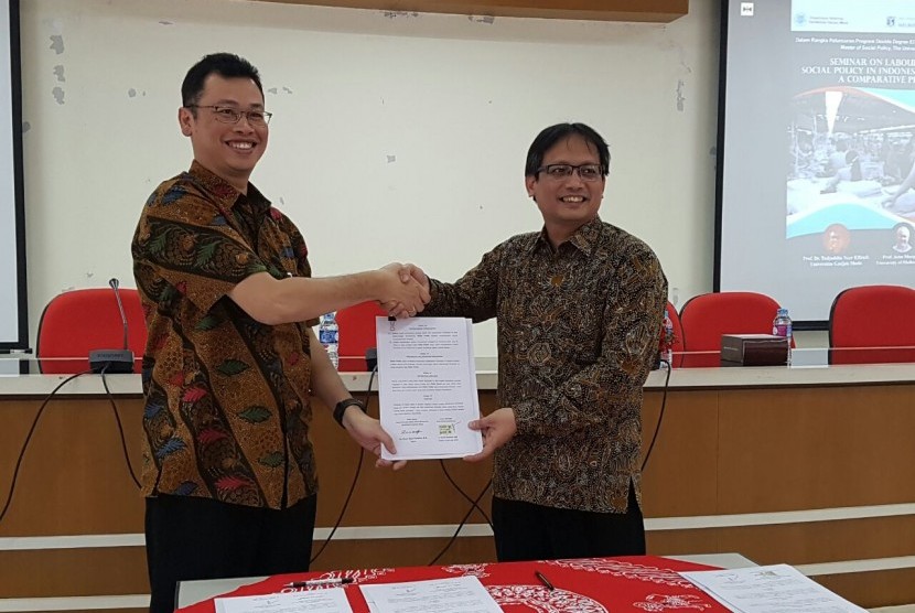 Dekan FISIP UGM Erwan Agus Purwanto (kiri) dan Direktur Umum dan SDM BPJS Ketenagakerjaan Naufal Mahfudz bersalaman seraya menunjukkan naskah kerja sama kedua lembaga di kampus UGM, Yogyakarta, Jumat (27/1).