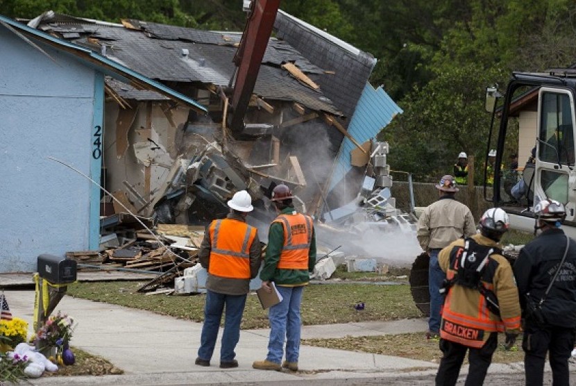 Demolition crews and Hillsborough County Fire Department watch as the house, where Jeffrey Bush was swallowed by a sinkhole, is demolished in Seffner, Florida March 3, 2013. 