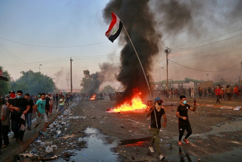 Demonstran antipemerintah melakukan pembakaran dan menutup jalan di Baghdad, Kamis (3/10).