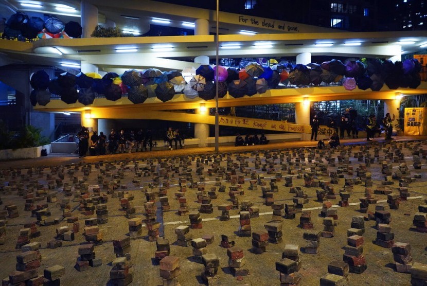 Demonstran berkumpul di kampus Hong Kong Baptist University yang dipenuhi payung dan jalanan diberi blokade tumpukan batu bata di Hong Kong, Rabu (13/11).