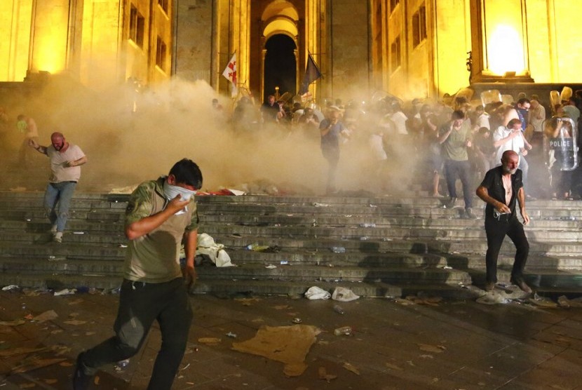 Demonstran berlarian saat polisi menembakkan gas air mata di depan Parlemen Georgia di Tbilisi, Georgia, Jumat (21/6).
