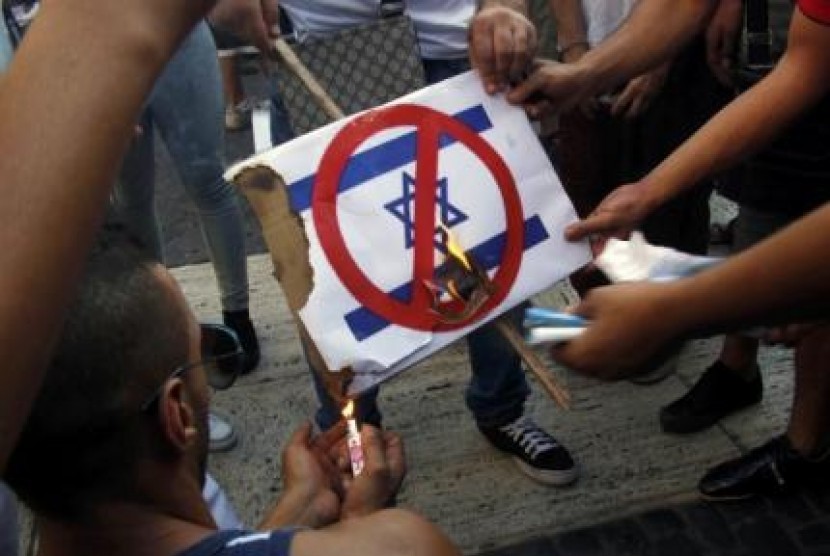 Demonstran di Barcelona, Spanyol membakar plakat bergambar bendera Israel dalam unjuk rasa menentang serangan Israel ke Jalur Gaza, Palestina, Kamis (17/7). Pada saat yang sama, gencatan senjata diberlakukan di Gaza.