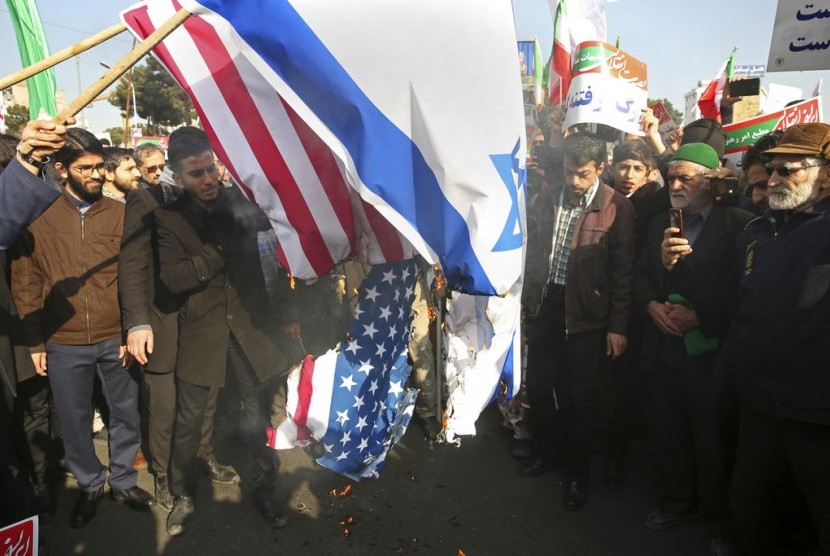 Demonstran Iran membakar bendera AS dan Israel di Mashhad, Iran, Kamis (4/1).