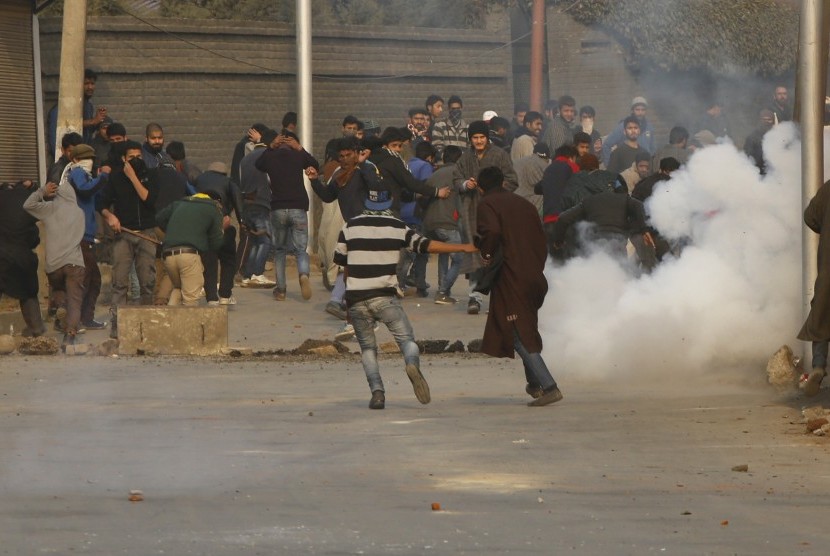Demonstran Kashmir berlindung dari asap gas air mata, saat protes terhadap Arab Saudi di Srinagar, Kashmir India.