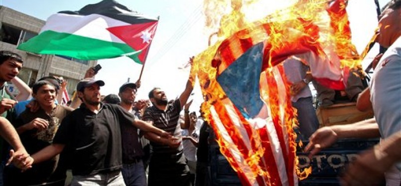Demonstran membakar bendera Amerika Serikat saat menggelar aksinya di Amman, Yordania, Jumat (22/7) waktu setempat.