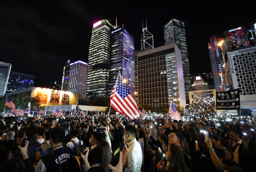 Demonstran memegang bendera AS di Hong Kong, Kamis malam (28/11). Demonstran merayakan tindakan Presiden AS Donald Trump yang menandatangi undang-undang yang mendukung otonomi Hong Kong. 