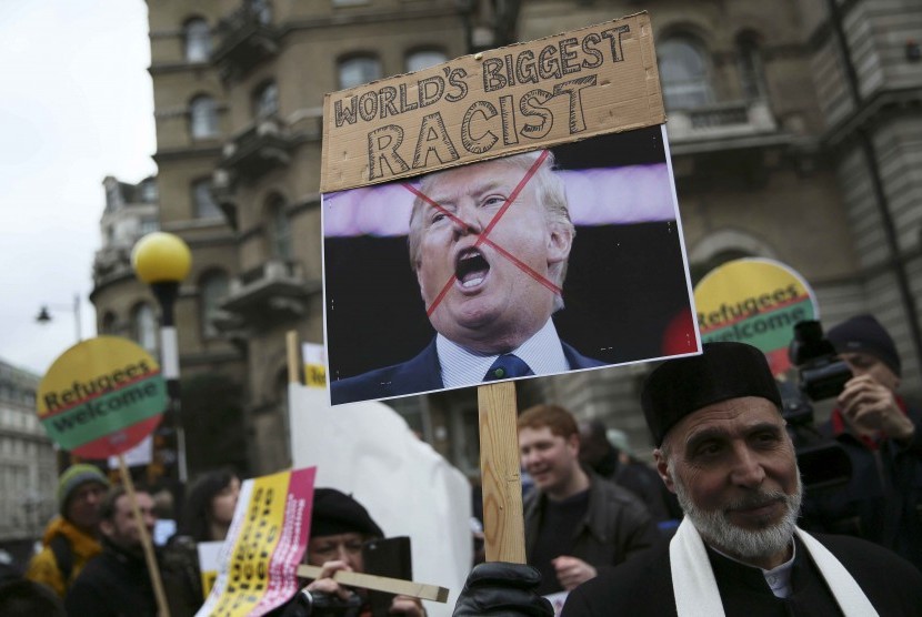 Demonstran memegang papan menunjukkan ketidaksukaannya pada Donald Trump dalam sebuah parade pengungsi di London.