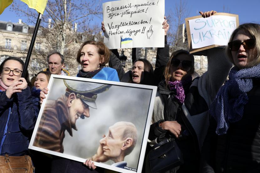 Demonstran memegang poster selama rapat umum sebagai protes terhadap invasi Rusia ke Ukraina, Sabtu, 26 Februari 2022 di Paris. 