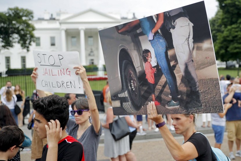 Demonstran memegang tulisan dan foto saat protes menentang kebijakan imigrasi Presiden Donald Trump yang memisahkan anak-anak dari orang tuanya di depan Gedung Putih, Kamis (21/6). Terdapat foto yang dijadikan sampul majalah Time edisi Juli 2018.