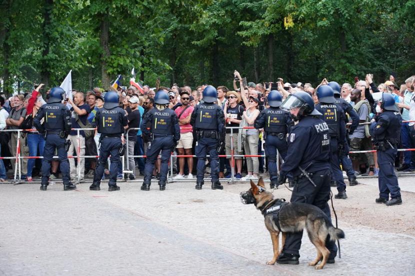 Aparat berjaga saat demonstran memprotes aturan pemerintah untuk mengendalikan pandemi virus corona di depan Gerbang Brandenburg di Berlin, Jerman, Sabtu (29/8).