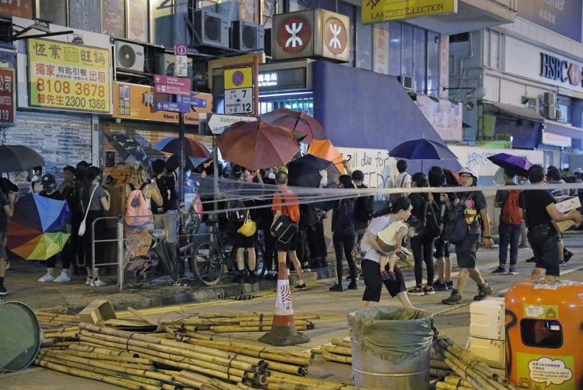   Demonstran menggunakan payung untuk menutupi dirinya saat menutup jalan di Mong Kok, Hong Kong, Jumat (6/9).