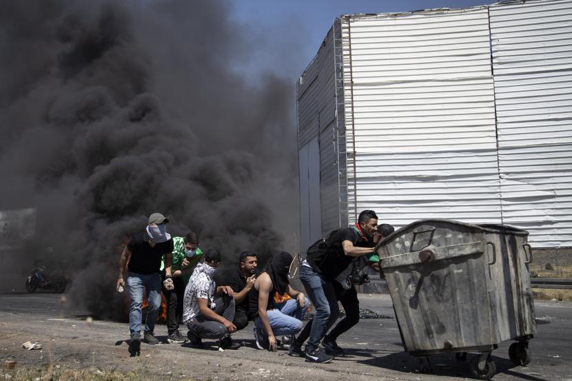 Kekerasan Meningkat, Biden Telepon Palestina dan Israel. Demonstran Palestina berlindung selama bentrokan dengan pasukan Israel di pos pemeriksaan Hawara, selatan kota Nablus, Tepi Barat, Jumat, 14 Mei 2021.