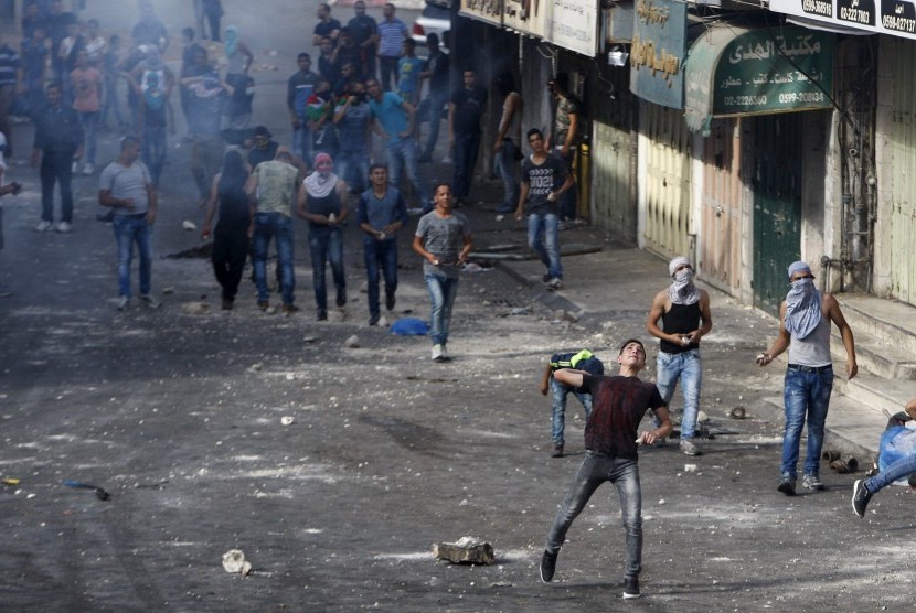 Demonstran Palestina melemparkan batu ke pasukan Israel selama bentrokan di Yerusalem al-Aqsa, di kota Tepi Barat yang diduduki Hebron 29 September 2015.