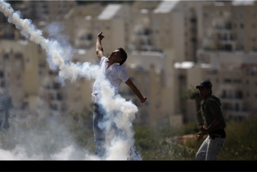 Demonstran Palestina melemparkan kembali tabung gas air mata yang dilepaskan tentara Israel saat aksi demonstrasi menentang pendudukan Israel di Tepi Barat, Ramallah, Jumat (13/4). 