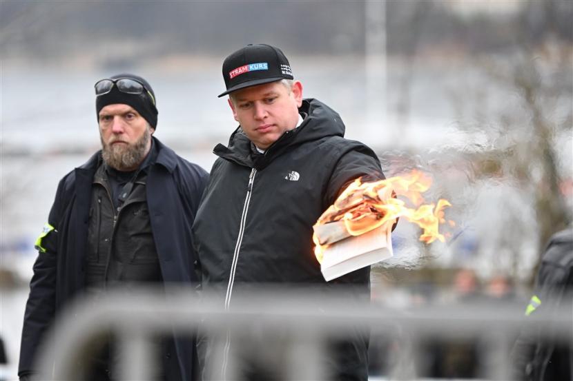 Dengan penjagaan polisi, pemimpin partai sayap kanan Stram Kurs (Garis Keras), Rasmus Paludan, membakar sebuah Alquran di depan Kedutaan Besar Turki di Ibu Kota Swedia, Stockholm, 21 Januari 2023. Mufti Besar Arab Saudi: Pembakaran Alquran di Swedia adalah Provokasi Terhadap Muslim