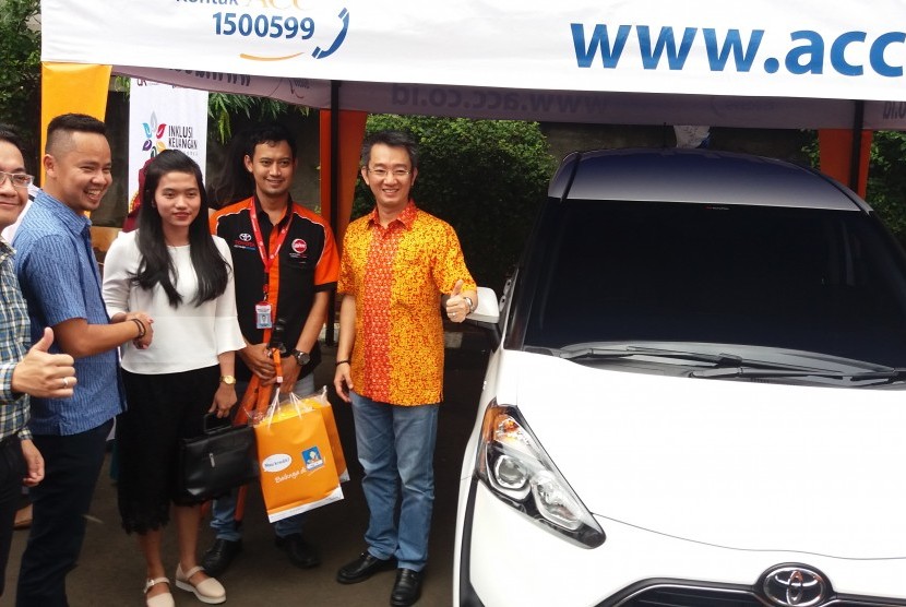 Deputy Chief Sales ACC Ezar Kumendang (kiri) dan Chief Operation Officer ACC Anton Rusli (baju oranye) menyerahkan satu unit mobil Toyota Sienta kepada konsumen bernama Puteri di sela acara Bazaar Sienta di Kantor ACC, Jakarta Selatan, Sabtu (22/10).