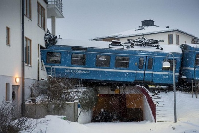 Derailed train that hangs on the edge of the track after it crashed into the side of a residential building in Saltsjobaden outside Stockholm, Tuesday Jan, 15, 2013.  